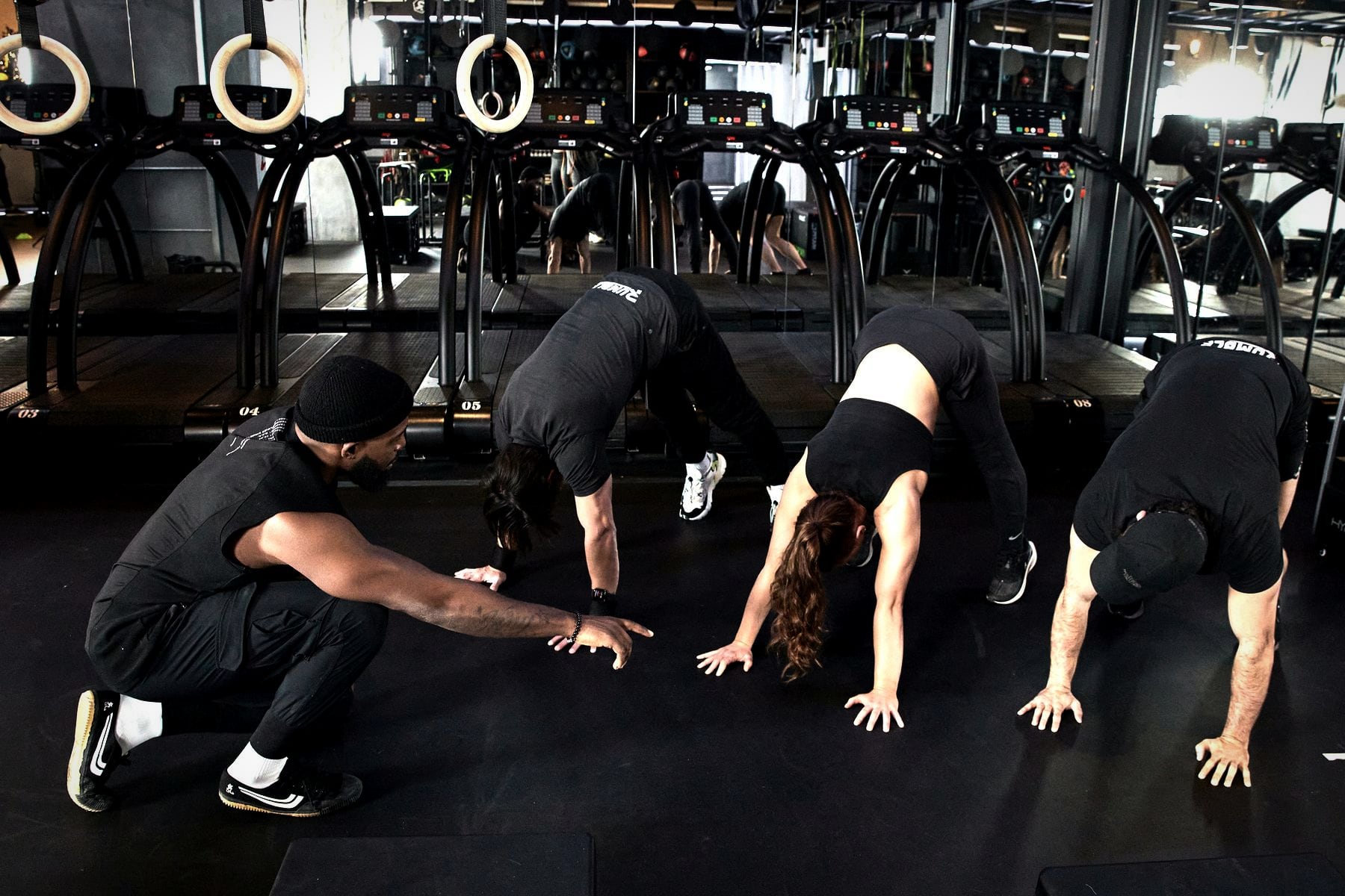A coach crouching to correct a member’s hand position during a group circuit at Rumble Dalston